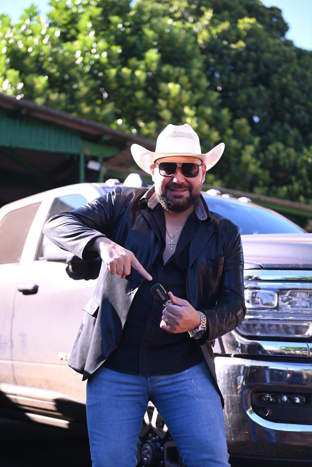Jeff da RAM de chapéu e óculos escuros, apontando para a chave de uma RAM branca estacionada atrás dele